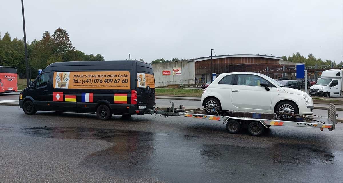 Transporter mit Fahrzeuganhänger auf nasser Strasse