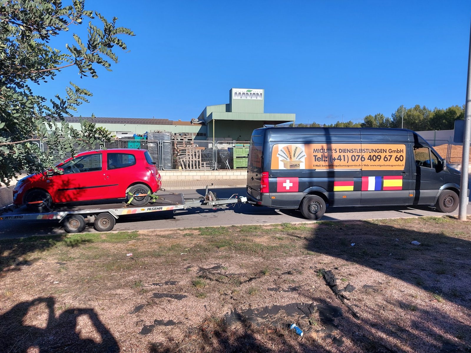 Transporter mit Fahrzeug auf dem Anhänger, Schweizer und spanische Fahne am Transporter