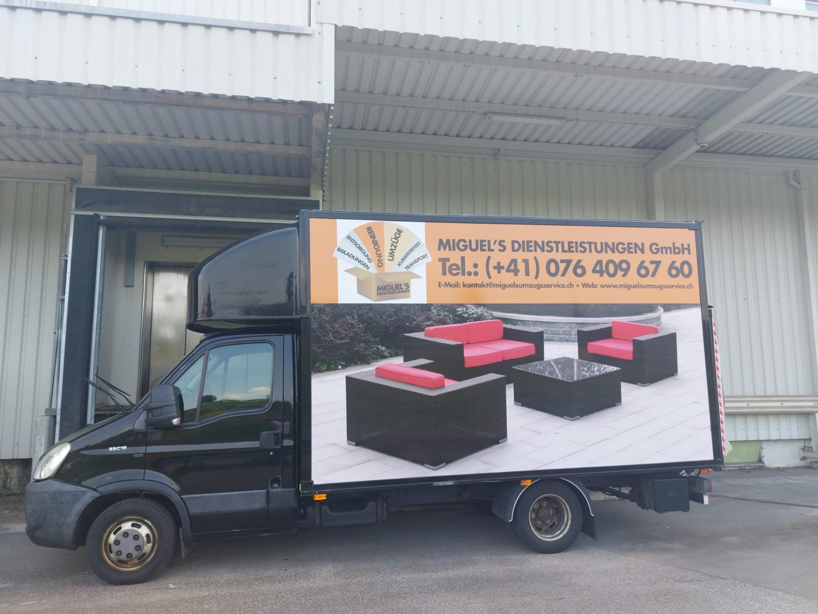 Schwarzer Lastwagen mit Beschriftung und Sofa-Motiv